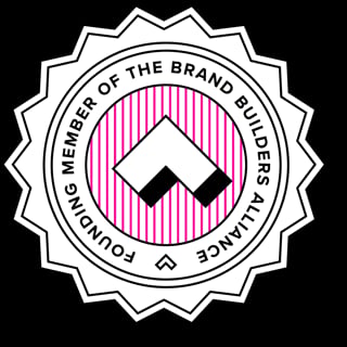 Circular seal badge with star-burst border, pink striped center, and geometric diamond symbol. Text reads Member of the Brand Builders Alliance around the edge.